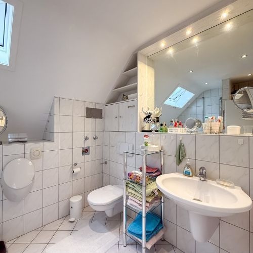 Modernes Badezimmer mit Dachfenster und weißen Fliesen in einer Maisonette-Eigentumswohnung in Krefeld.