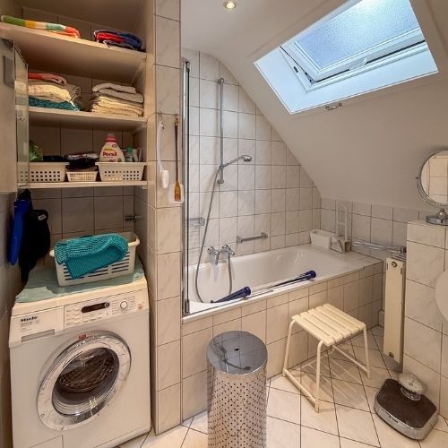 Praktisch gestaltetes Badezimmer mit Badewanne, Platz für Waschmaschine und Tageslicht in einer Maisonette-Wohnung in Krefeld.