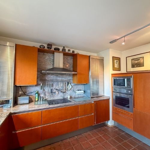 Zeitlose Einbauküche mit hochwertigen Holzelementen, Granitarbecken und Edelstahlgeräten in einer Maisonette-Wohnung.