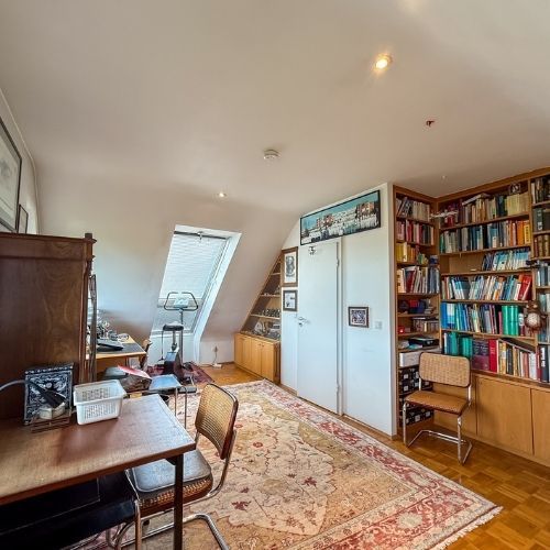 Geräumiges Dachgeschoss-Arbeitszimmer mit Einbauschrank, Parkettboden und Dachfenster in einer Maisonette-Wohnung.