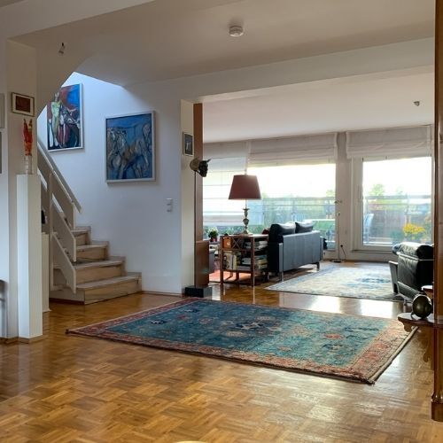 Offener Wohnbereich mit Parkettboden, Marmortreppe und großem Fenster zur Terrasse in einer modernen Maisonette-Eigentumswohnung in Krefeld.