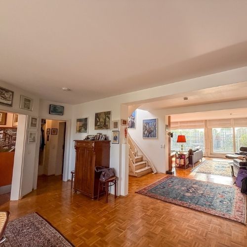 Großzügige Diele mit Parkettboden und Durchgang zum hellen Wohnzimmer mit Balkon.